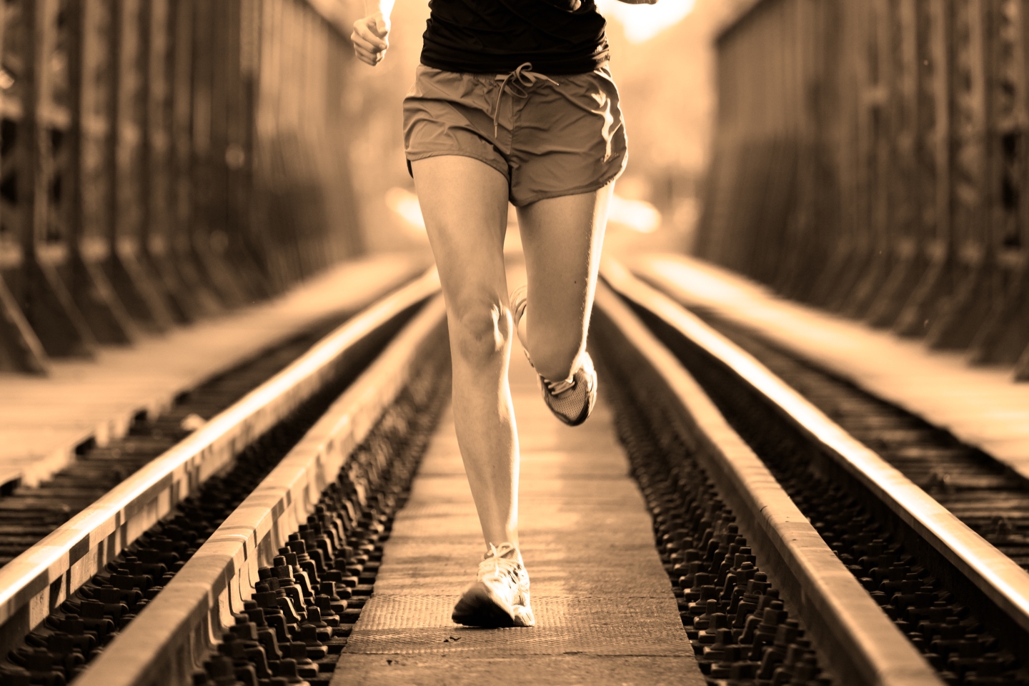 Active female athlete running on railaway tracks.